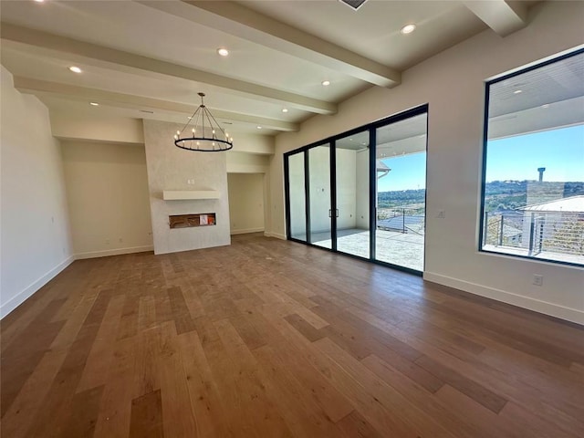 unfurnished living room with a fireplace, beam ceiling, a chandelier, and hardwood / wood-style floors