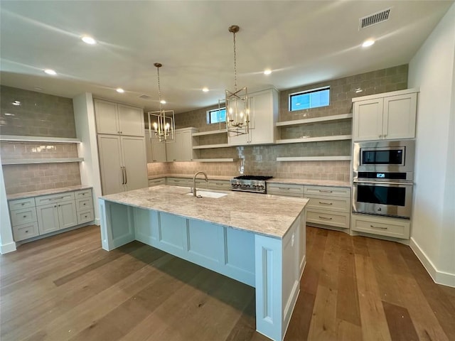 kitchen featuring sink, white cabinetry, hanging light fixtures, a large island with sink, and appliances with stainless steel finishes