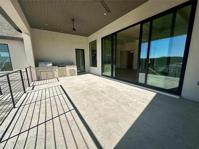 wooden terrace featuring a grill, ceiling fan, and an outdoor kitchen