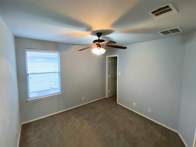 unfurnished room with ceiling fan and dark carpet