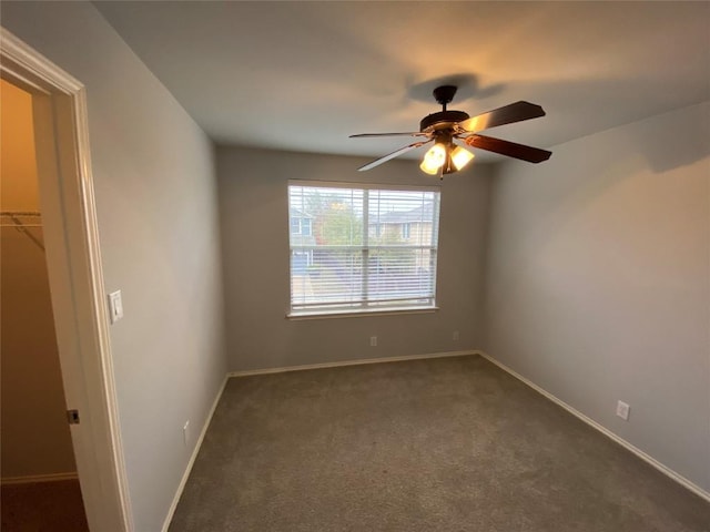 empty room with ceiling fan and dark carpet