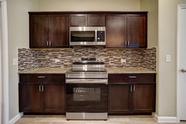 kitchen with dark brown cabinetry, appliances with stainless steel finishes, backsplash, and light stone counters