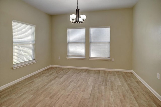 spare room featuring a notable chandelier and light hardwood / wood-style floors