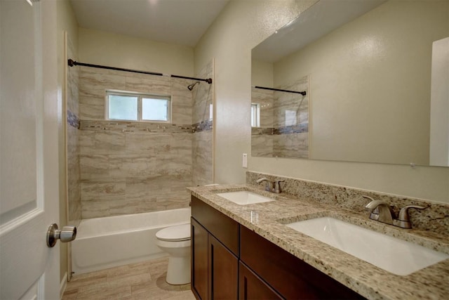 full bathroom featuring vanity, tiled shower / bath, and toilet