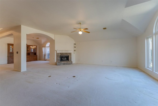 unfurnished living room featuring vaulted ceiling, ceiling fan with notable chandelier, light carpet, and a fireplace