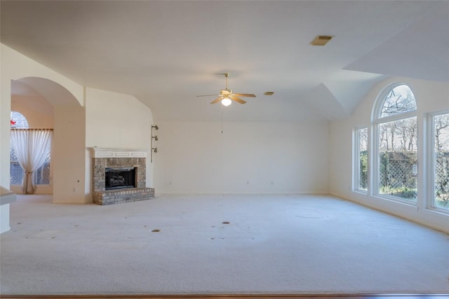 unfurnished living room with ceiling fan, light colored carpet, vaulted ceiling, and a brick fireplace