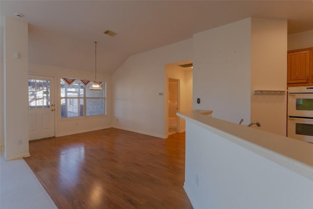 unfurnished dining area featuring lofted ceiling, sink, and hardwood / wood-style floors