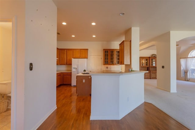 kitchen featuring a kitchen island, kitchen peninsula, light hardwood / wood-style flooring, and white fridge with ice dispenser