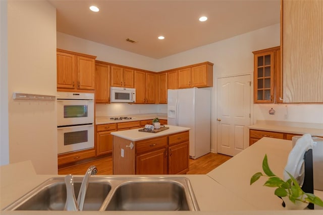 kitchen with white appliances, light hardwood / wood-style floors, sink, and a kitchen island