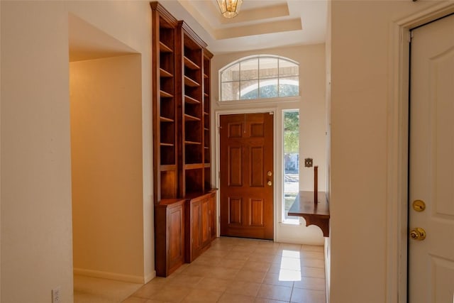 foyer with light tile patterned floors and a tray ceiling