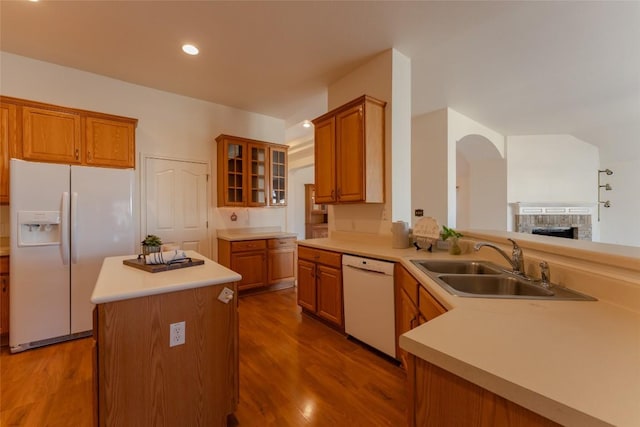 kitchen featuring sink, white appliances, hardwood / wood-style floors, a center island, and kitchen peninsula