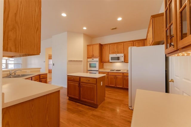 kitchen featuring a kitchen island, sink, white appliances, and light hardwood / wood-style flooring