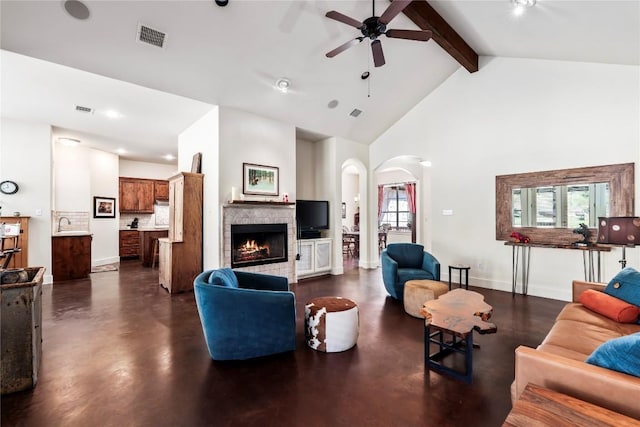 living room featuring beamed ceiling, ceiling fan, high vaulted ceiling, and a tile fireplace