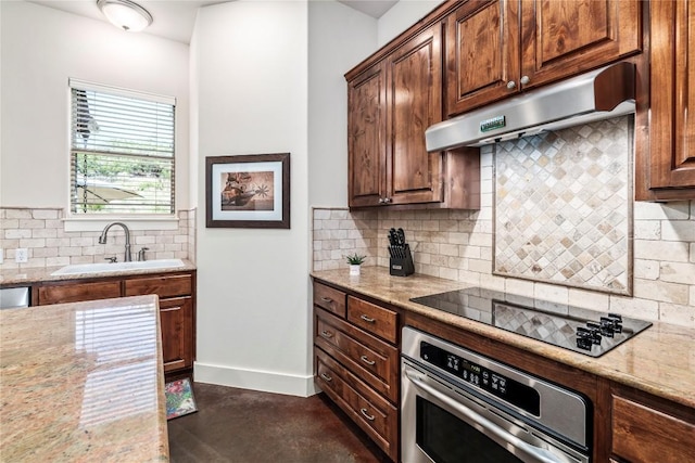 kitchen featuring sink, backsplash, black electric stovetop, light stone countertops, and stainless steel oven