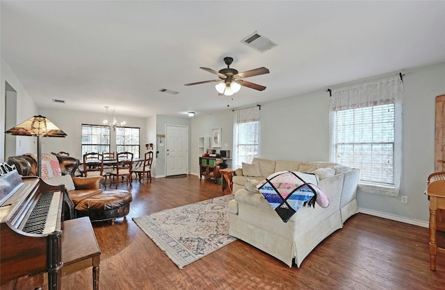 living room featuring a healthy amount of sunlight, ceiling fan with notable chandelier, and dark hardwood / wood-style flooring