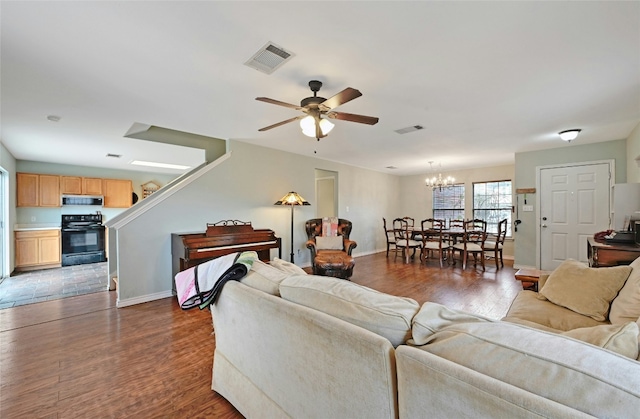 living room with dark wood-type flooring and ceiling fan with notable chandelier