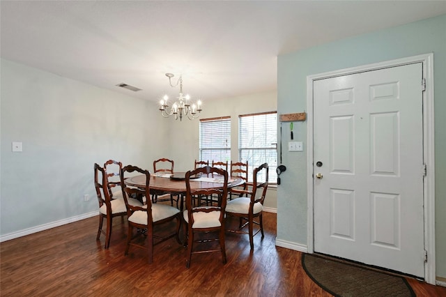 dining space with dark wood-type flooring and an inviting chandelier