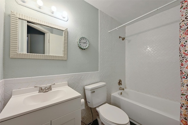 full bathroom with tiled shower / bath combo, vanity, tile walls, and toilet