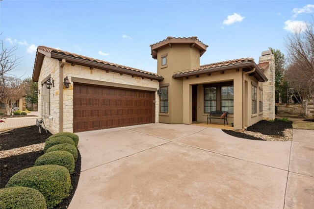 204 Delfino Cir, Lakeway, TX 78734 - mediterranean / spanish-style home featuring an attached garage, stone siding, concrete driveway, a tile roof, and stucco siding