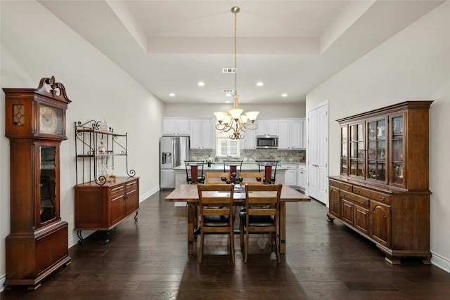 dining space with a chandelier, dark hardwood / wood-style flooring, and a tray ceiling