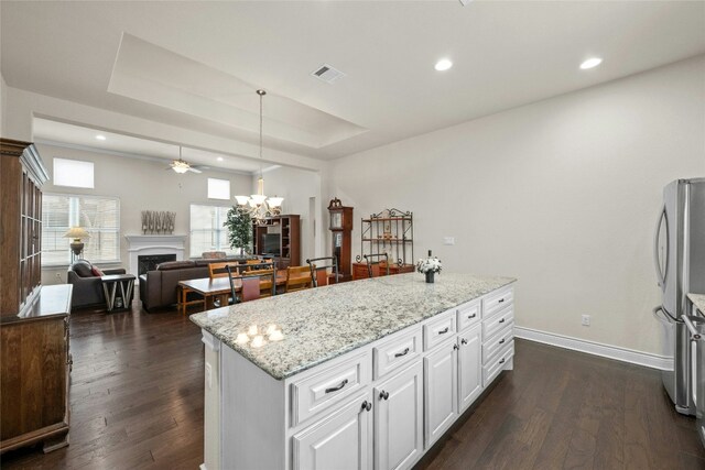 204 Delfino Cir, Lakeway, TX 78734 - kitchen featuring a fireplace, freestanding refrigerator, dark wood-type flooring, light stone countertops, and white cabinetry