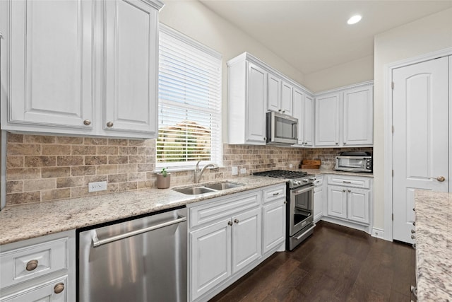 kitchen featuring sink, appliances with stainless steel finishes, light stone counters, white cabinets, and dark hardwood / wood-style flooring