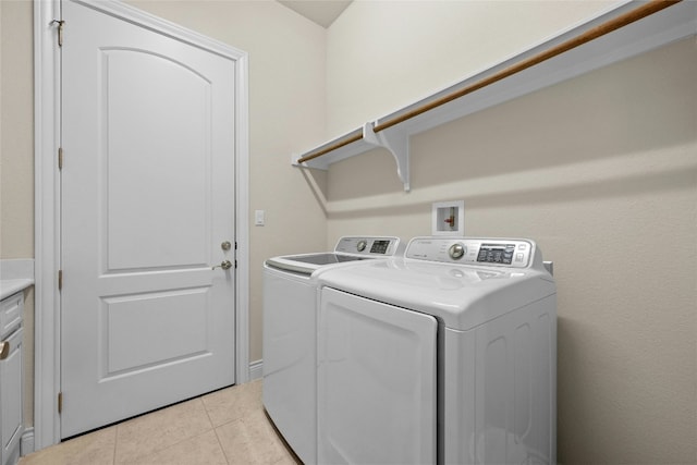 clothes washing area with washer and dryer and light tile patterned floors