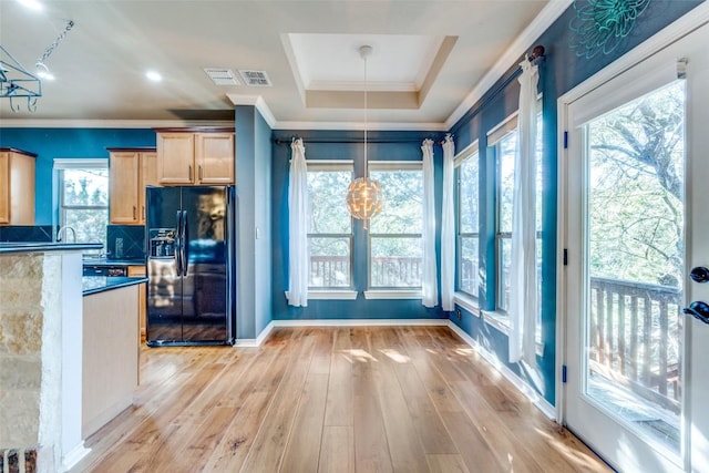 interior space featuring hanging light fixtures, black fridge with ice dispenser, plenty of natural light, and light brown cabinets