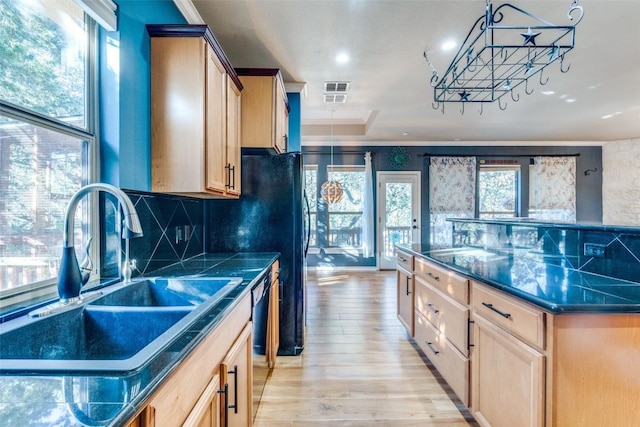 kitchen featuring a kitchen island, dishwasher, sink, backsplash, and light hardwood / wood-style flooring