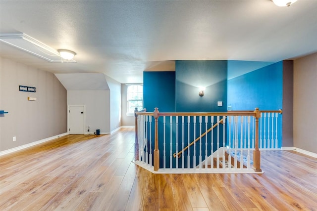 additional living space with vaulted ceiling, hardwood / wood-style floors, and a textured ceiling