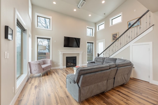 living room with a towering ceiling and light wood-type flooring