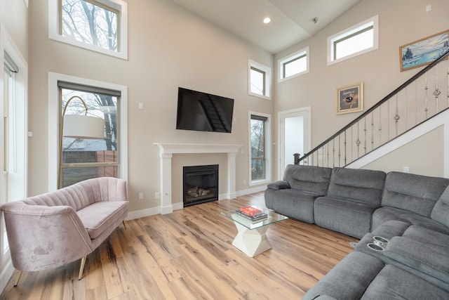 3301 Rockhurst Ln, Austin, TX 78723 - living room with a towering ceiling, light wood finished floors, a glass covered fireplace, stairs, and recessed lighting