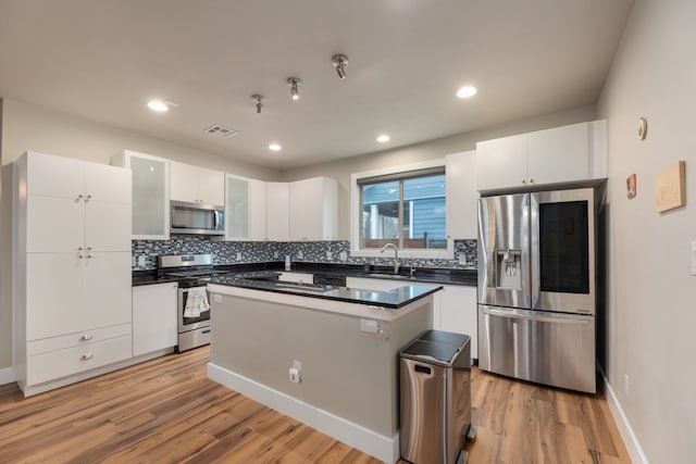 3301 Rockhurst Ln, Austin, TX 78723 - kitchen with stainless steel appliances, dark countertops, white cabinetry, decorative backsplash, and recessed lighting
