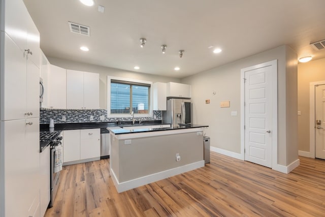 3301 Rockhurst Ln, Austin, TX 78723 - kitchen featuring appliances with stainless steel finishes, dark countertops, white cabinets, backsplash, and light wood-type flooring