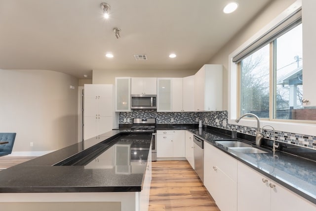 kitchen featuring sink, white cabinetry, a center island, light wood-type flooring, and stainless steel appliances