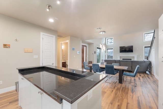 3301 Rockhurst Ln, Austin, TX 78723 - kitchen featuring light wood finished floors, white cabinetry, healthy amount of natural light, open floor plan, and recessed lighting