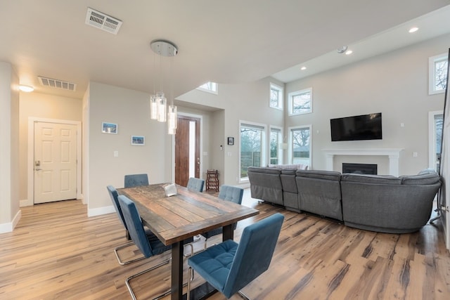 dining space with a towering ceiling and light hardwood / wood-style flooring