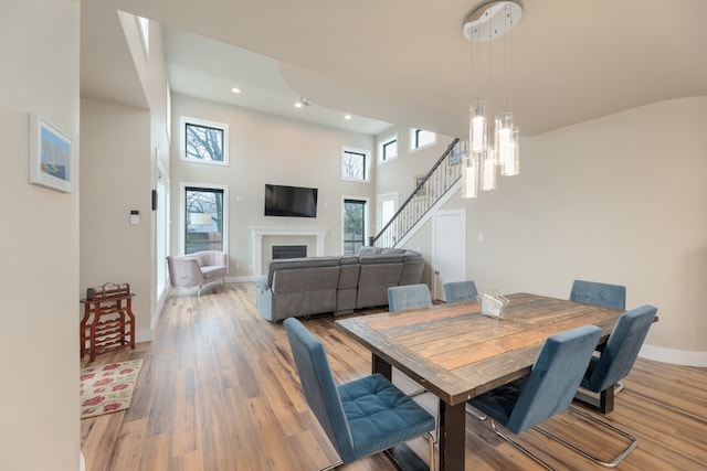 3301 Rockhurst Ln, Austin, TX 78723 - dining space with light wood-style floors, a fireplace, recessed lighting, stairs, and a high ceiling