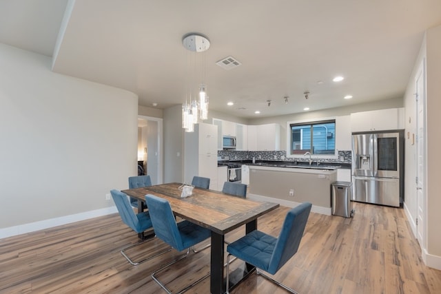 dining space with sink and light wood-type flooring