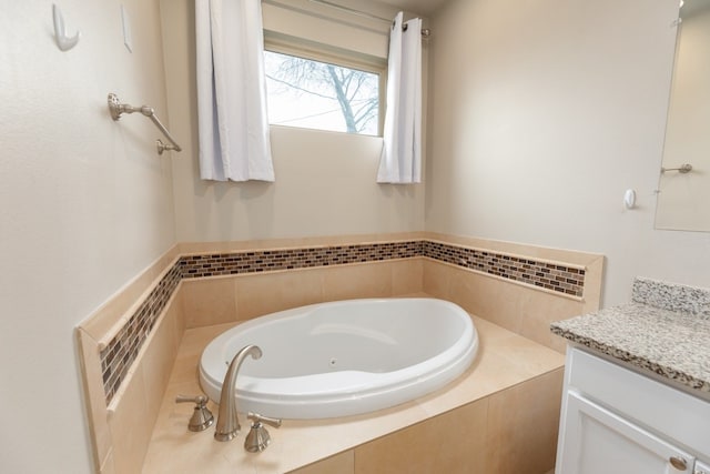 bathroom featuring tiled tub and vanity