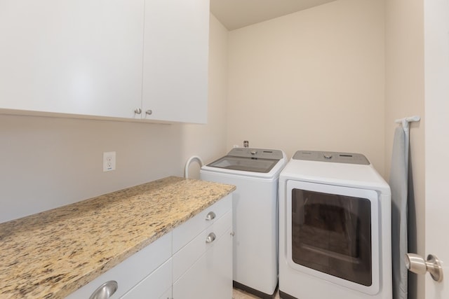 clothes washing area featuring cabinets and washer and clothes dryer