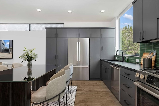 kitchen featuring sink, gray cabinetry, backsplash, stainless steel appliances, and light hardwood / wood-style flooring