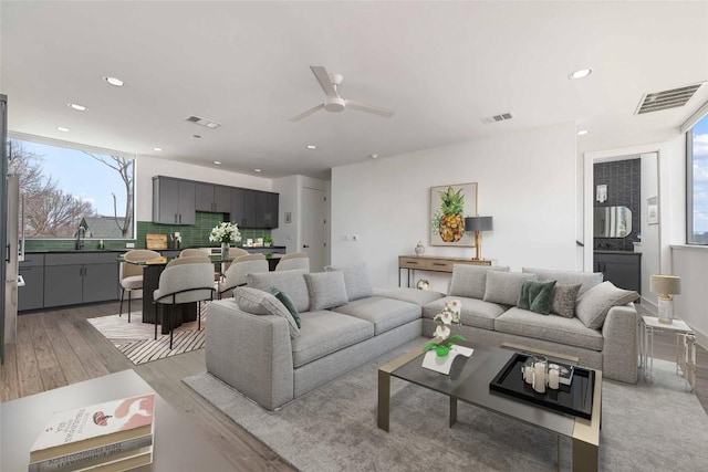 living room with ceiling fan, sink, and light hardwood / wood-style floors