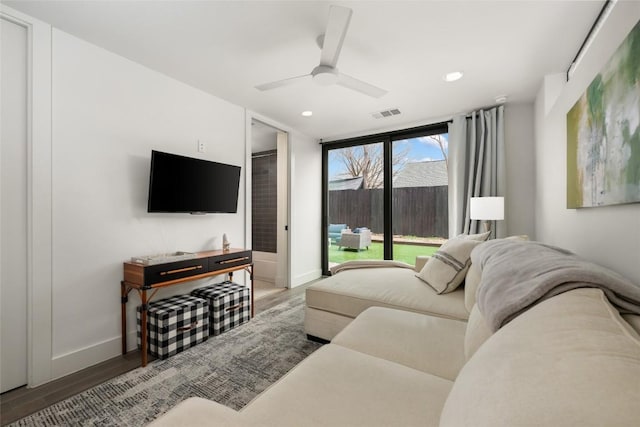 living room featuring hardwood / wood-style flooring, ceiling fan, and a wall of windows