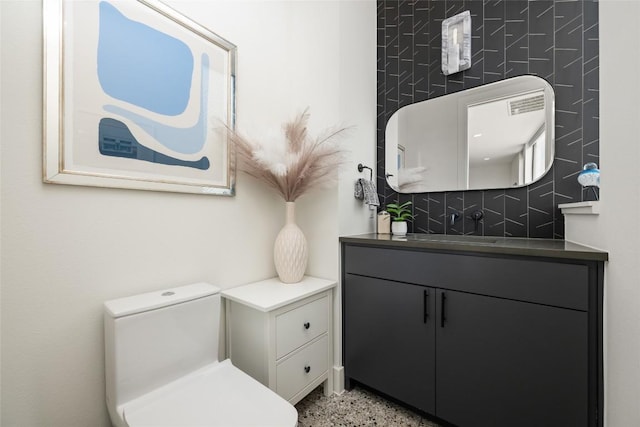 bathroom with vanity, toilet, and decorative backsplash