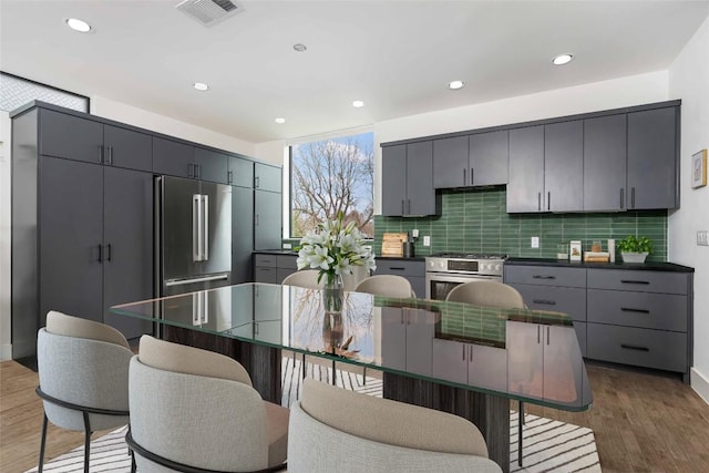 kitchen featuring built in refrigerator, tasteful backsplash, hardwood / wood-style flooring, and a center island