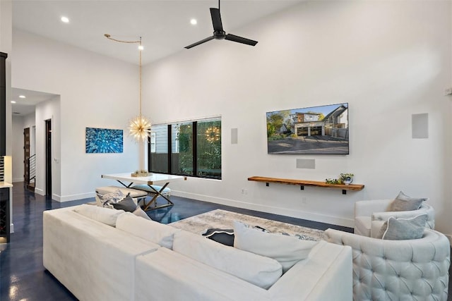 living room featuring a high ceiling and ceiling fan with notable chandelier