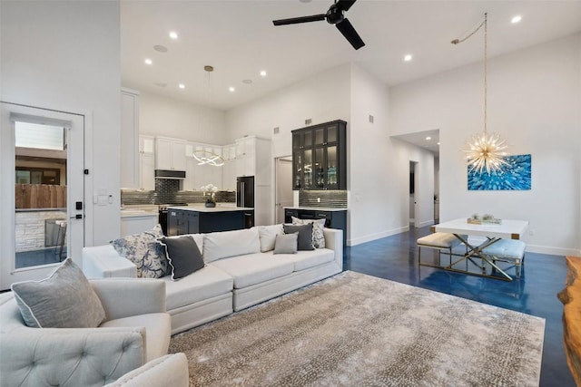 living room featuring a high ceiling, dark wood-type flooring, and ceiling fan with notable chandelier