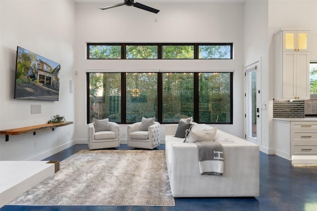 living room featuring ceiling fan and a high ceiling