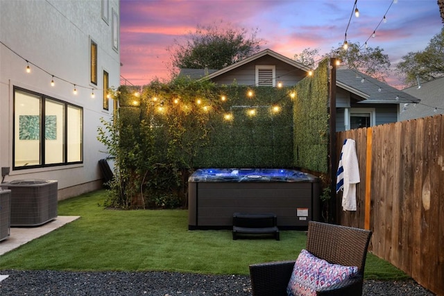 yard at dusk with cooling unit and a hot tub